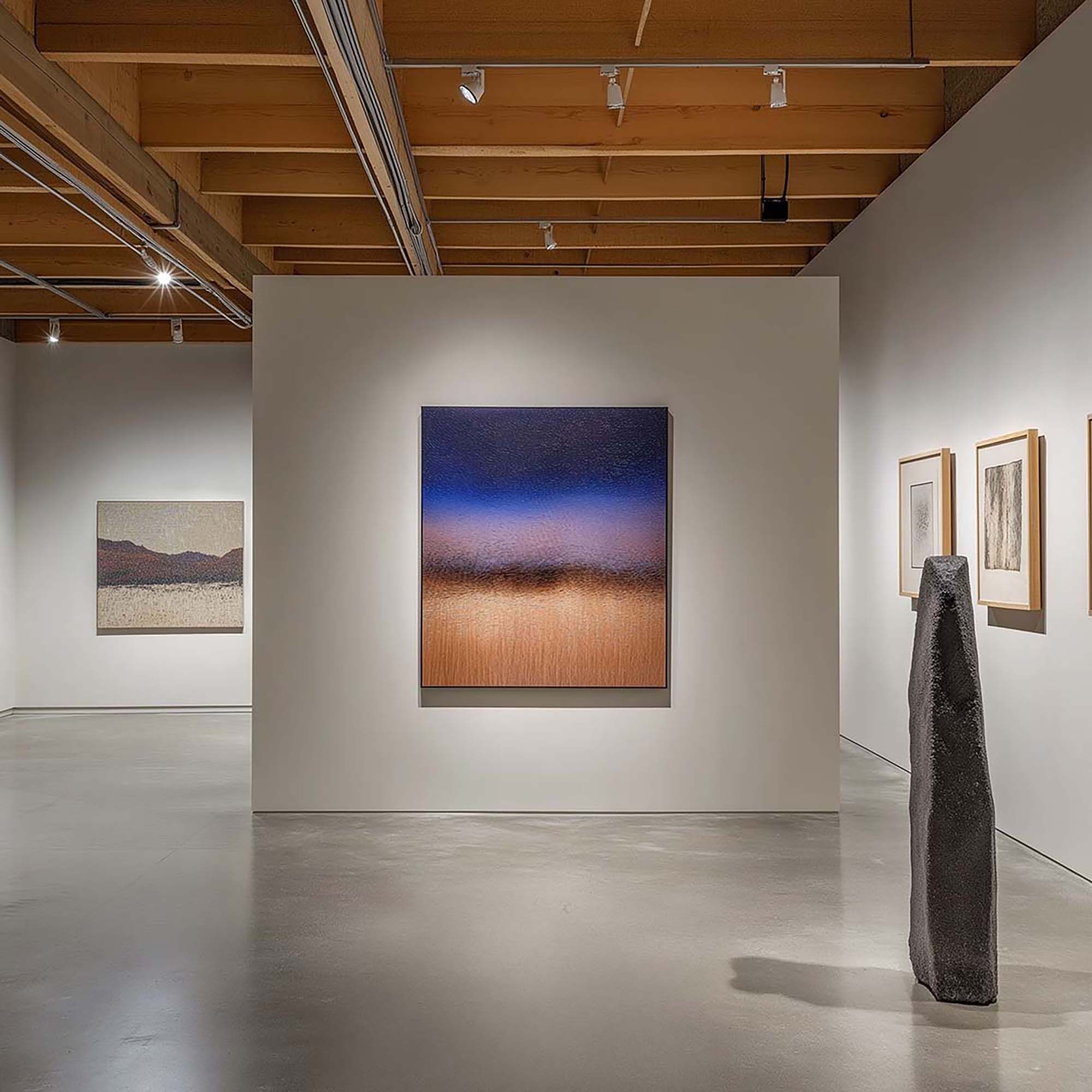 Modern gallery interior with a large framed artwork centered on a freestanding white wall under track lighting.
